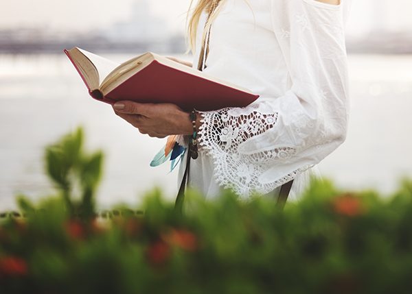 mujer leyendo un libro sobre tecnología en verano, cerca del mar