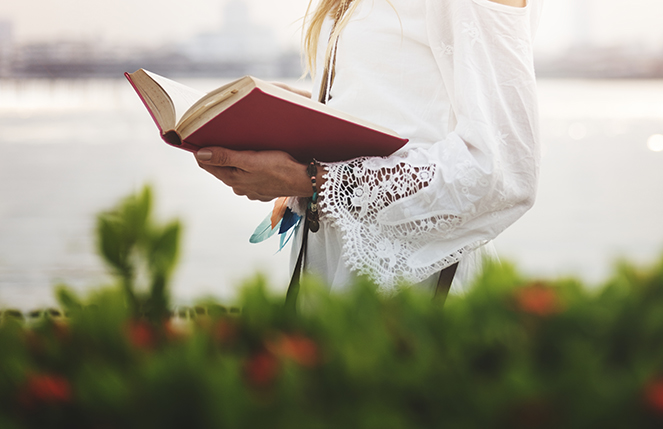 mujer leyendo un libro sobre tecnología en verano, cerca del mar